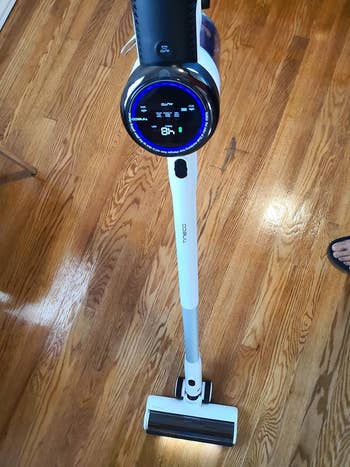reviewer's Tineco stick vacuum with the LED light on and digital controls lit up
