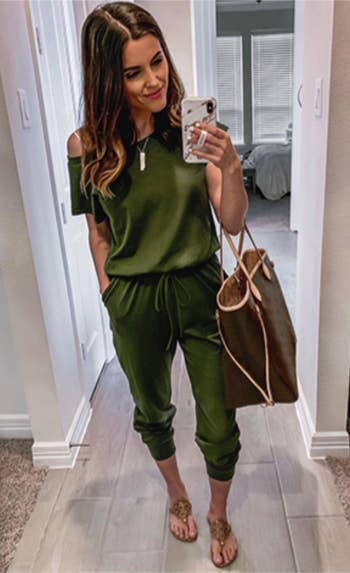 model successful  a casual greenish  off-shoulder jumpsuit and sandals takes a reflector  selfie holding a spacious tote bag