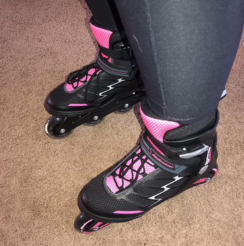 Reviewer wearing pink and black skates with black leggings