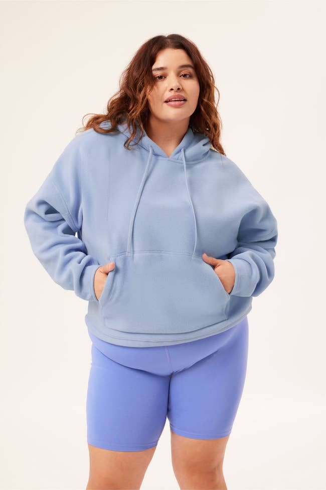 a model in a light blue fleece hooded sweatshirt