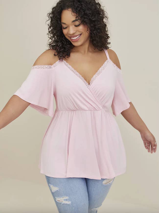 Model in V-neck lace-edged pink empire waist top with cut out shoulders 