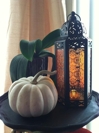 the black lantern with amber glass next to a pumpkin