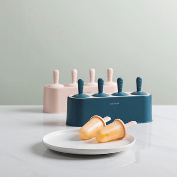 pink and blue popsicle molds with two orange popsicles on a plate in front of them