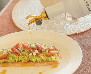 model drizzling the dressing on avocado toast