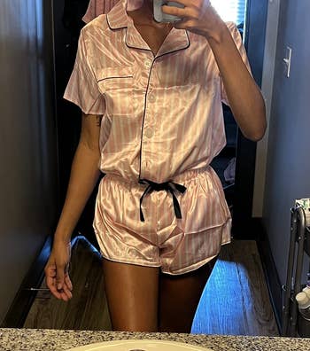 a reviewer wearing the pair of pink-striped satin pajamas