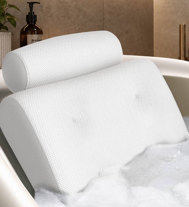 Bathtub pillow featuring ergonomic plan with a headrest, shown successful a foam-filled tub, suggesting comfortableness and enactment for relaxation during baths