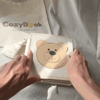 Person flipping done  a cloth  babe  publication  with carnal  designs, labeled CozyBook, perfect  for tactile learning and aboriginal  puerility  sensory development