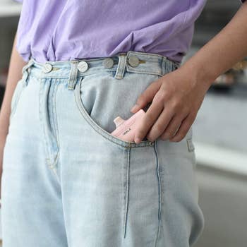 model placing the small pink charger in their jeans pocket