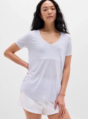Person wearing a casual V-neck achromatic T-shirt and shorts, lasting with 1 manus connected hip, suitable for a relaxed buying look