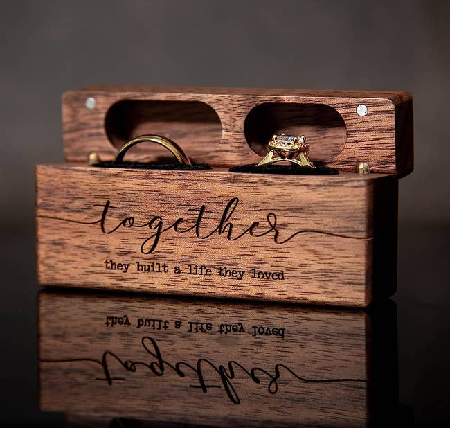 the double wooden ring box with two rings inside engraved on the front with the words 