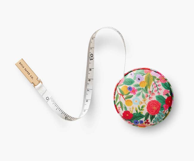 a floral circular measuring tape case with a tape measure extended from it