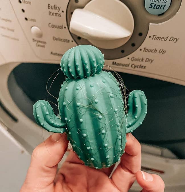image of reviewer holding up the cactus-shaped dryer ball which is covered in hair