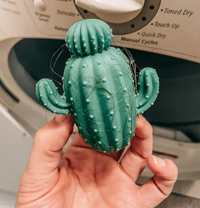 image of reviewer holding up the cactus-shaped dryer ball which is covered in hair
