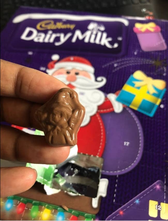 Reviewer holding up a Santa shaped chocolate next to an advent calendar 