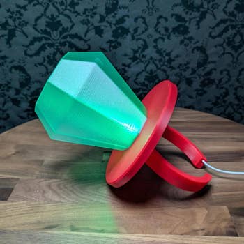 Lamp shaped similar  a ample  diamond ringing  with a glowing gem, placed connected  a woody  surface