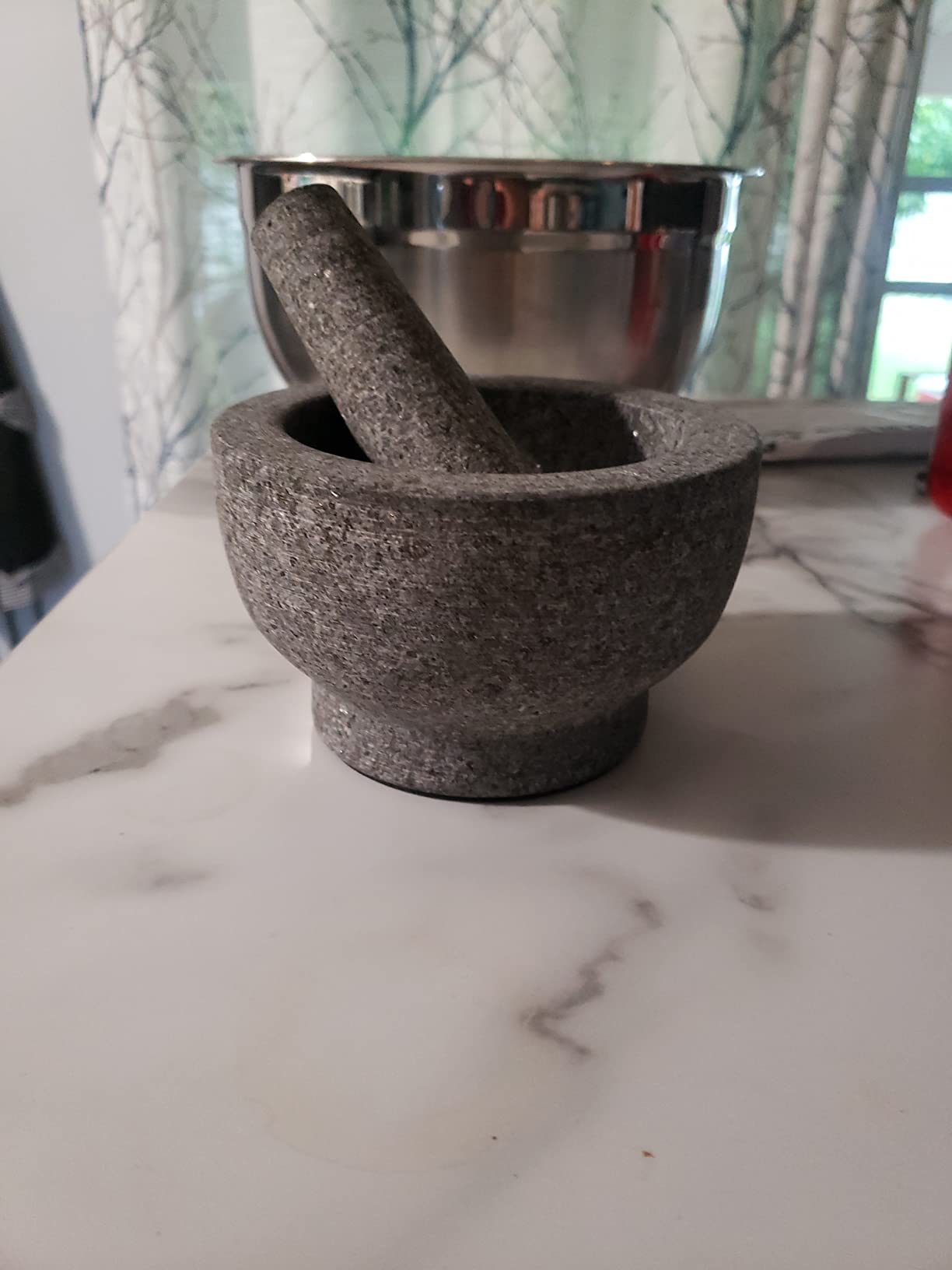 Granite mortar and pestle acceptable   connected  a marble countertop with a metallic  vessel  successful  the background, suitable for grinding and mixing ingredients
