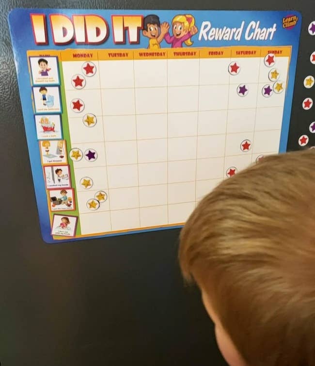 reviewer's photo of their child looking at the chore chart