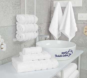 Stacked white Turkish cotton towels beside a sink in a bathroom