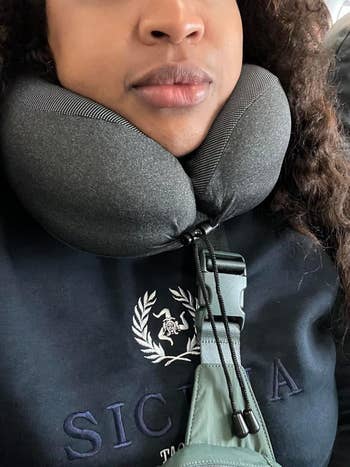 Person utilizing a cervix  pillow portion    traveling, wearing a sweatshirt with a tiny  emblem. The representation  suggests comfort-related question   accessories