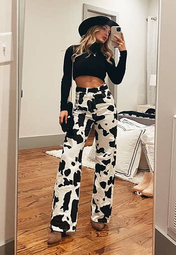 a reviewer taking a mirror selfie in the cow print pants