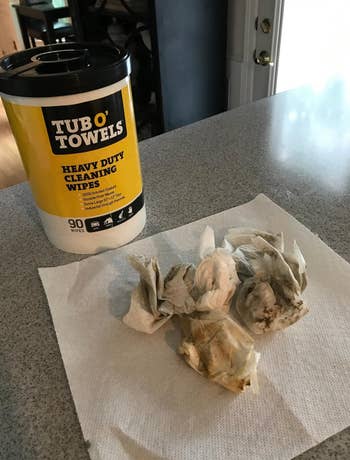 Container of Tub O' Towels heavy-duty cleaning wipes adjacent  to utilized  wipes connected  a insubstantial  towel connected  a countertop
