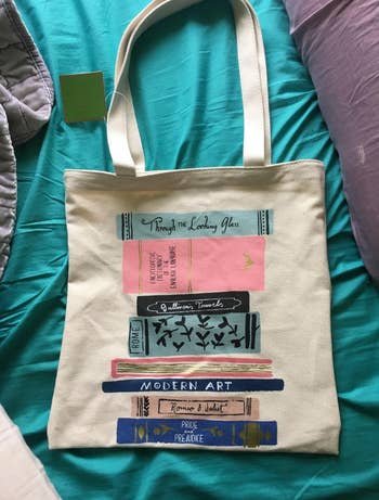 A canvas tote bag with illustrated classic novels stacked on top of each other 