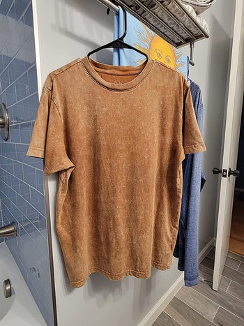 same reviewer's after photo showing the t-shirt looking wrinkle-free after being treated with the wrinkle releaser spray