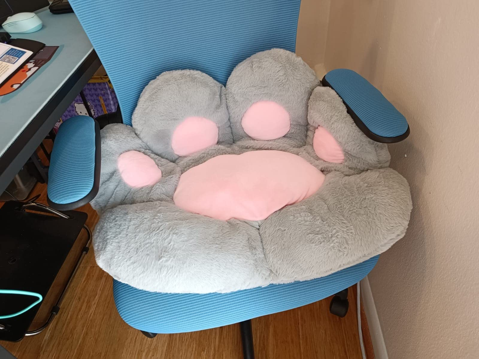 Plush chair shaped like a cat's paw, with four pink pads, on a blue office chair
