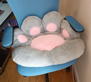 Plush chair shaped like a cat's paw, with four pink pads, on a blue office chair