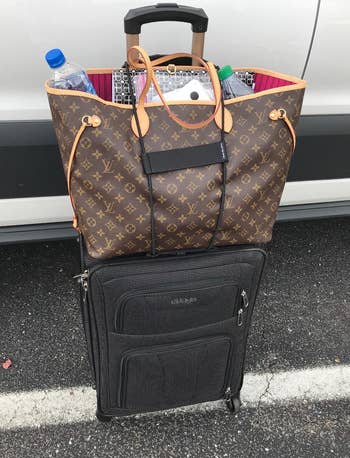 a reviewer's black suitcase with a Louis Vuitton Never Full bag bungeed to the top