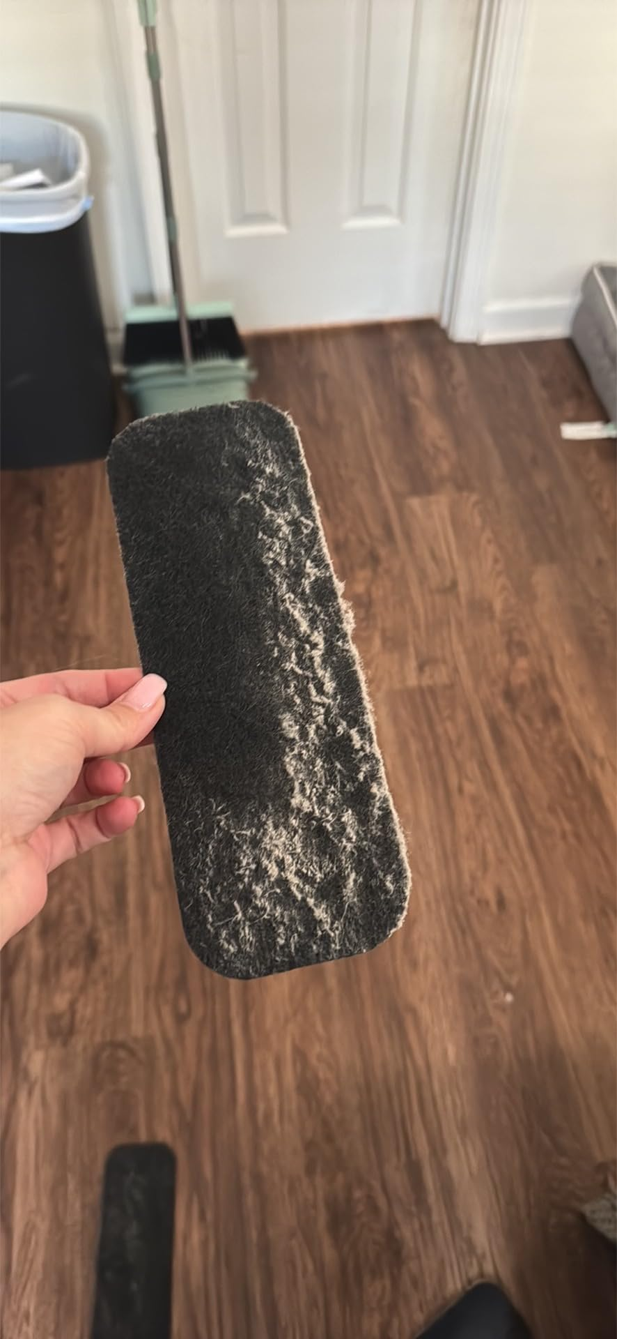 Hand holding a lint roller expanse  filled with favored  hair, implicit    a hardwood floor, demonstrating cleaning effectiveness