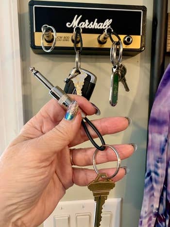 Reviewer holding a jack plug key ring with their keys attached and the Marshall amplifier key holder in the back