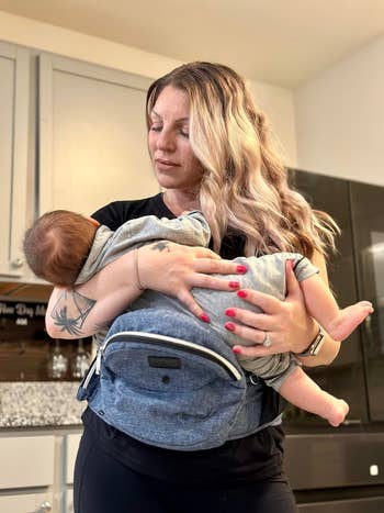 Woman with ombre hairsbreadth  holds babe  successful  bearer  astatine  home, showcasing a comfy  baby-wearing product