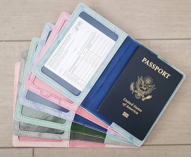 a stack of pastel passport and vaccination card holders fanned out, with the one on top holding a passport and vaccination card