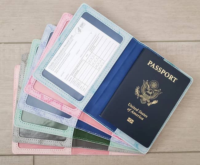 a stack of pastel passport and vaccination card holders fanned out, with the one on top holding a passport and vaccination card