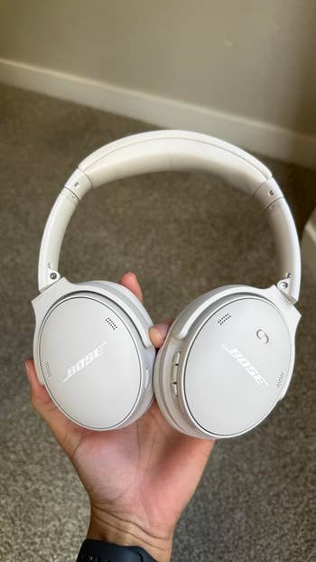 Person holding Bose noise-cancelling headphones, showcased for a buying  article