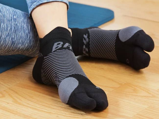 Model in black compressive split toe socks with gray detailing 