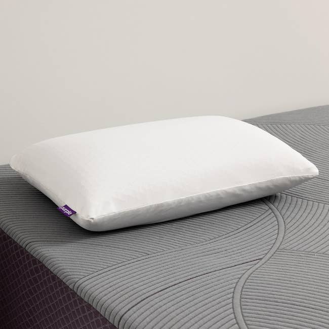 A white pillow with a simple design sits on a textured mattress, highlighting bedding options