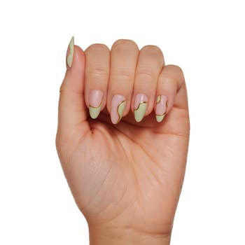 A hand with nail art nails with lines and light green segments