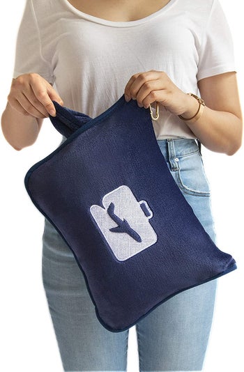 model pulling the navy blanket out of its carrying case