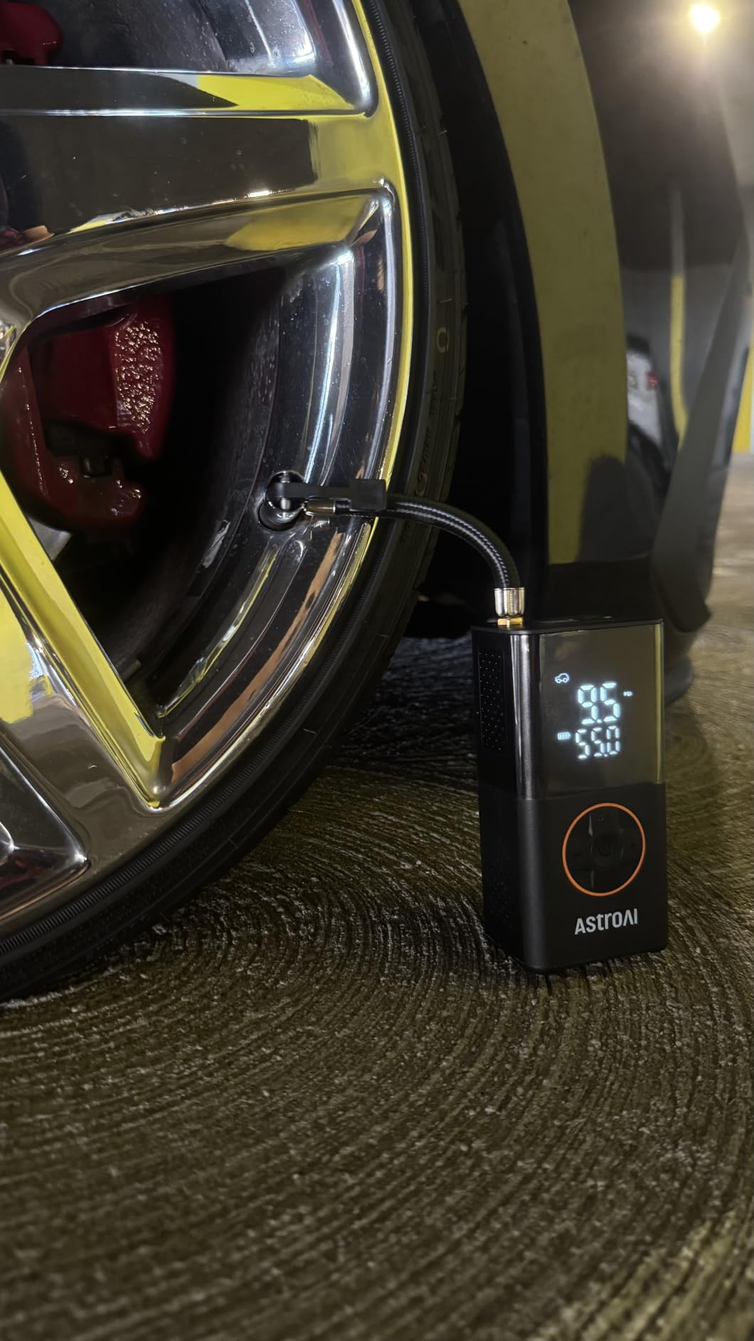 Portable tyre  inflator connected to a car   tire, displaying unit   astatine  9.5 PSI