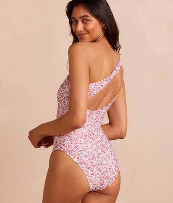 Model posing in a floral one-piece swimsuit