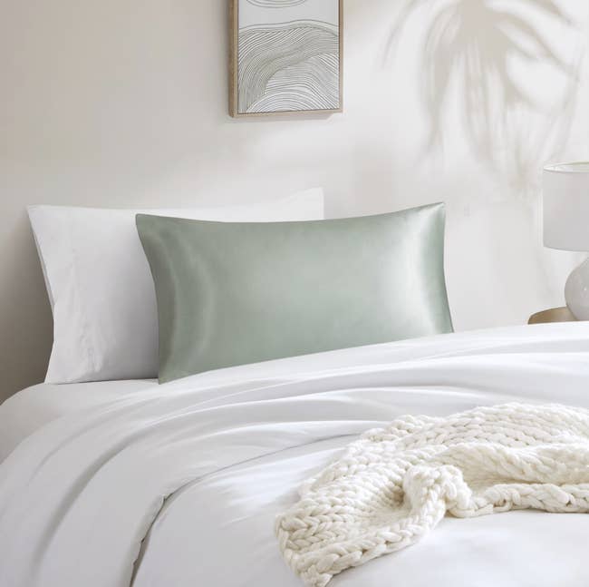 Silk pillowcase connected a neatly made furniture with a woven blanket, promoting luxury bedding options for a comfy and stylish chamber setup