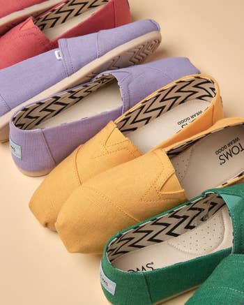 Various TOMS shoes in a range of solid colors displayed for shopping selection