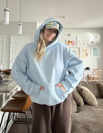 Person successful a relaxed room mounting wearing a cozy hoodie, cap, and comfy pants, adjacent to a room antagonistic with stools and decor