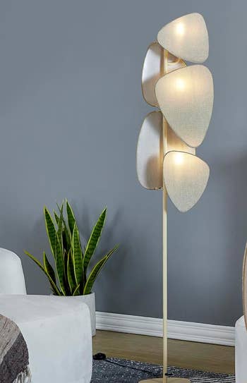 Floor lamp with sculptural shades next to a potted plant, in a living room setting