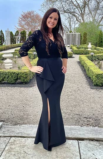Reviewer wearing black V-neck lace long sleeve dress with ruffle slit and mermaid skirt outside on stone ground