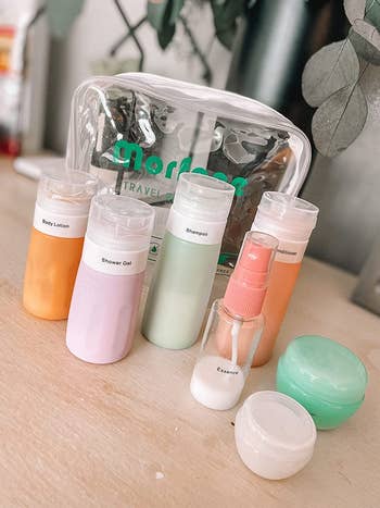reviewer shows the same colorful bottles from the set all filled with liquid shampoo, conditioner, etc.