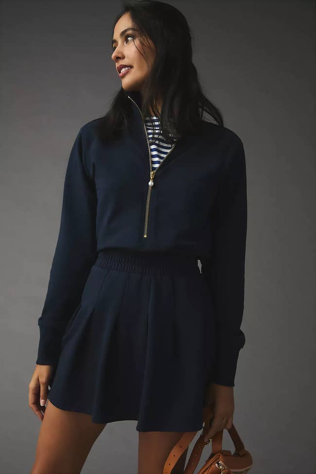 model in long sleeve navy mini dress with elastic waist and gold front zipper