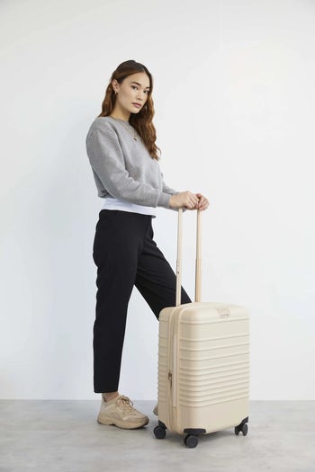 model posing with beige suitcase